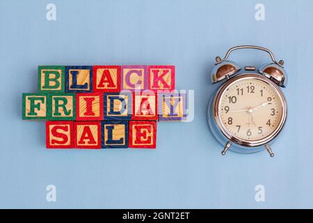 SPEKTAKULÄRES KONZEPT VON SCHWARZEM FREITAG UND VERKAUF MIT HOLZWÜRFELN UND HOLZOBERFLÄCHE MIT ALTEM WECKER. Stockfoto