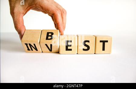 Symbol für beste Investition. Geschäftsmann dreht Holzwürfel und ändert das Wort „investieren“ in „am besten“. Schöner weißer Hintergrund. Geschäft und beste Investitionen conce Stockfoto