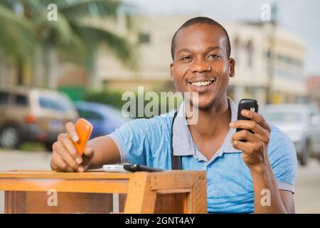 homme souriant assis à une Cabine téléphonique Stockfoto