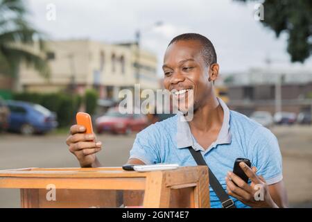 jeune travailleur souriant avec des téléphones en mains Stockfoto