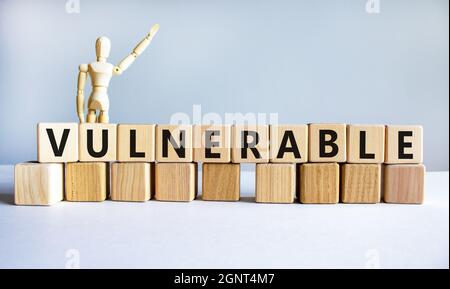 Anfälliger Symbol. Das Wort verwundbar auf Holzwürfeln. Holzmodell des Menschen. Symbol für Geschäftsleute. Schöner weißer Hintergrund. Geschäftliche und anfällige c Stockfoto