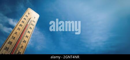Holzthermometer mit roter Messflüssigkeit, die eine hohe Temperatur von über 33 Grad Celsius auf dem Hintergrund des blauen Himmels zeigt. Panorama. Konzept der Wärme wav Stockfoto