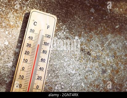 Holzthermometer mit roter Messflüssigkeit, die am sonnigen Tag auf altem Steingrund eine hohe Temperatur von über 32 Grad Celsius anzeigt. Konzept der Wärme wa Stockfoto