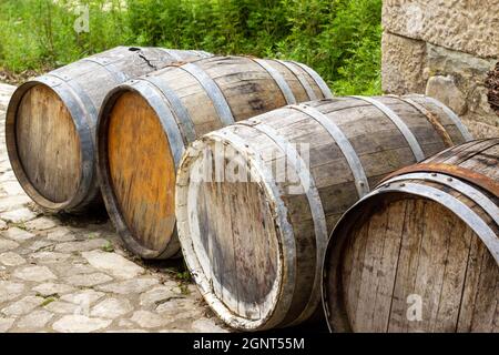 Alte Holzfässer. Altes Holzfass mit Metallringen auf schönem Hintergrund. Gestapelter Stapel alter Vintage-Whisky- und Weinholzfässer. Konzeptionell Stockfoto