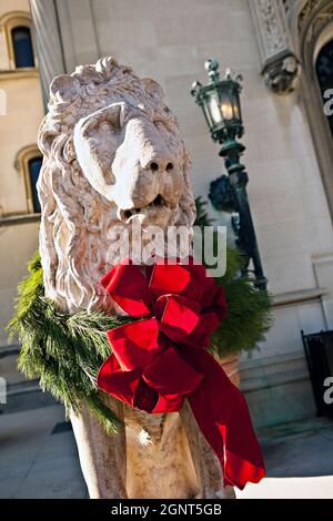 Eine mit einem Weihnachtsbogen geschmückte Statue eines Schutzlöwens im Biltmore Estate, das im Herbst in Asheville, North Carolina, im Privatbesitz der Familie Vanderbilt ist. Das Haus ist das größte Privathaus in Amerika mit über 250 Zimmern. Stockfoto