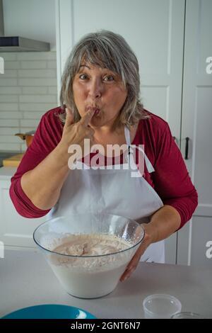 Ältere Frau, die einen Kuchen macht Stockfoto