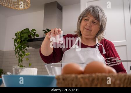 Ältere Frau, die einen Kuchen macht Stockfoto