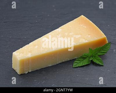 Ein Stück Parmigiano-Käse auf Schieferplatte, Parmesan mit grünem Blatt Stockfoto