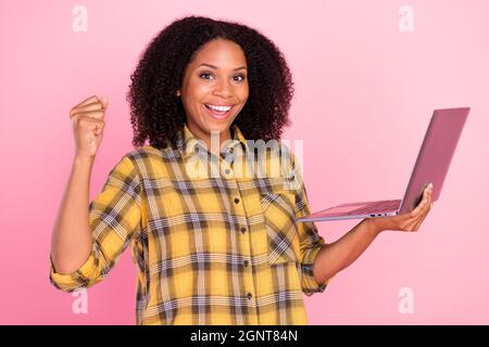 Foto von staunte verrückte Dame halten Laptop heben Faust Triumph Errungenschaft tragen karierte Hemd isoliert rosa Farbe Hintergrund Stockfoto