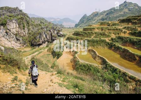 Sapa, Vietnam - 15. April 2016: Frau (Black Hmong), die in nationaler Kleidung durch die Hügel Südostasiens wandert. nordvietnamesische Berge in Stockfoto