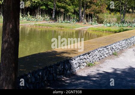 Eine Bank neben einem Teich im Railroad Park in Birmingham, Alabama Stockfoto