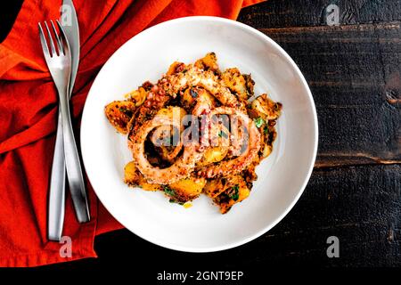 Spanish Style Octopus mit Kartoffeln: Zartes Tintenfisch serviert mit gebräunten Kartoffeln und gelben Paprika Stockfoto