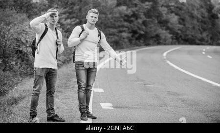 Art zu reisen. Nur Freunde und Weg voraus. Spüren Sie die Freiheit. Reisen mit Freunden. Fahren Sie mit dem Auto-Stop. Hoffnungsloser Anhalter. Männer versuchen, das Auto zu stoppen Stockfoto