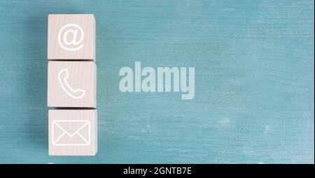 Symbole für E-Mail, Telefon und Newsletter auf Holzblöcken, blauer Hintergrund Stockfoto