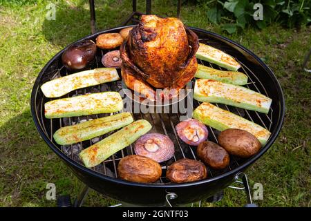Hühnerkarkasse und Gemüse auf einem Holzkohlegrill gebacken und geräuchert Stockfoto