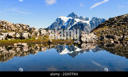 Mount Shuksan spiegelt sich an einem Tag mit blauem Himmel im Herbst auf dem Artist Ridge Trail im Nordwesten des Staates Washington in einem Wasserbecken Stockfoto