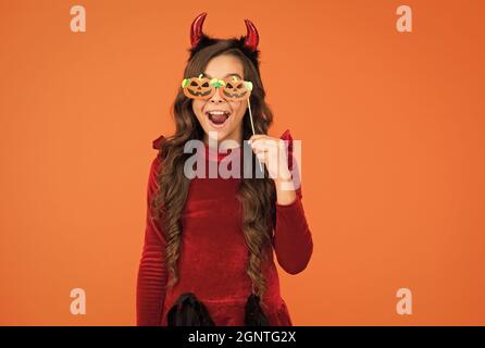 Was für eine Überraschung. Kid tragen Teufelshörner. Kind mit lustigen Partei Attribut. Teen Mädchen hat lockiges Haar und tragen Kleid für Feiertagsfeier. Herbst Stockfoto