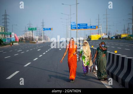 Ghaziabad, Indien. September 2021. Lokale Frauen gehen während eines landesweiten Streiks gegen die Agrarreformen an der Grenze zwischen Delhi und Uttar Pradesh auf einer verlassenen Straße.Tausende indische Bauern blockierten den Verkehr auf wichtigen Straßen und Eisenbahnlinien an mehreren Stellen von morgens an, als die von der Samyukta Kisan Morcha (Bauerngewerkschaft) eingeleitete Schließung, Ein Dachverband von 40 Bauerngewerkschaften begann, die Blockade wurde um 4 Uhr aufgehoben. Kredit: SOPA Images Limited/Alamy Live Nachrichten Stockfoto