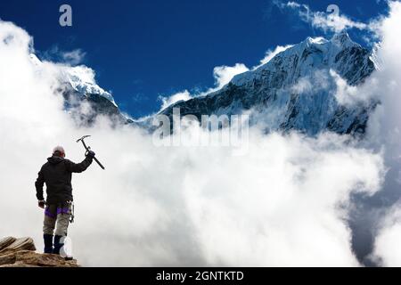 Silhouette des Menschen mit Eispickel in der Hand und in den Bergen Mit Wolken - Mount Thamserku und Mount Kangtega - Nepal Stockfoto