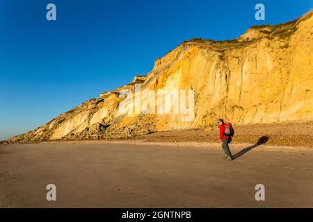 Frau, die am Strand von Alum Bay and Cliffs, Isle of Wight, Großbritannien, spazieren geht Stockfoto