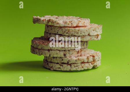 Sieben runde gesunde Brote stehen in einer Säule vor einem hellgrünen Hintergrund. Stockfoto