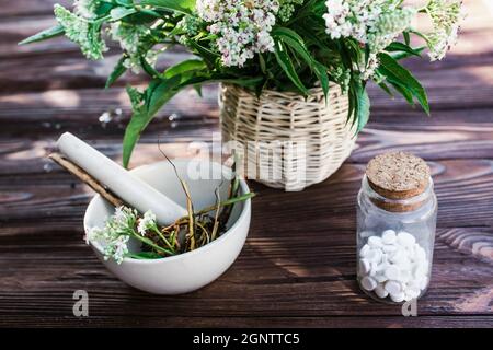 Baldrian-Tabletten mit beruhigenden Eigenschaften. Pharmazeutisches Glas mit Pillen auf einem Holztisch. Kochen Baldrianwurzel in einem Mörser für Kräuterelixiere. S Stockfoto