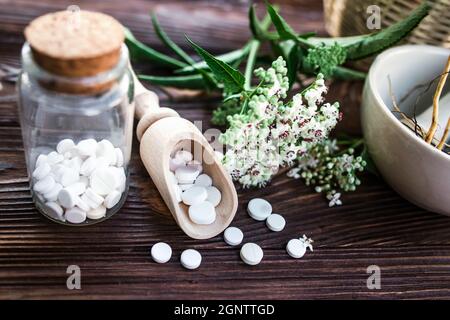 Baldrian-Tabletten mit beruhigenden Eigenschaften. Pharmazeutisches Glas mit Pillen auf einem Holztisch. Kochen Baldrianwurzel in einem Mörser für Kräuterelixiere. S Stockfoto