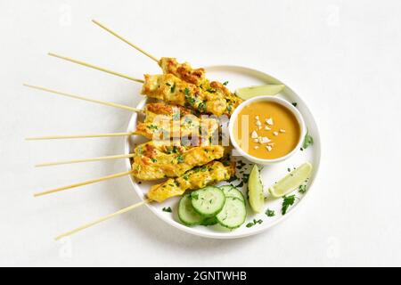 Nahaufnahme von Hühnersatay mit Erdnusssauce auf weißem Hintergrund. Stockfoto