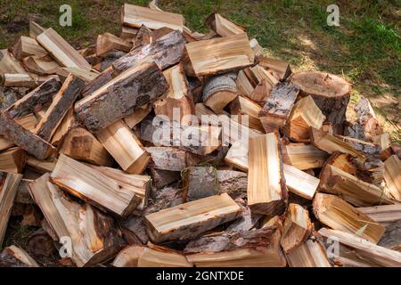 Gehacktes Holz in einem Haufen draußen, für den Winter vorbereitet, um das Haus zu heizen. Brennstoff für Herd und Kamin. Stockfoto