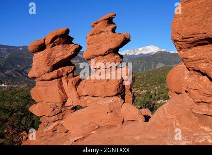 Blick auf den Pikes-Gipfel durch das Loch in der roten Felsformation der Siamesischen Zwillinge im Park Garden of the Gods in Colorado Springs, Colorado, USA Stockfoto