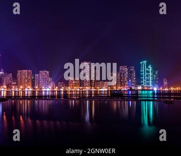 Wunderschöner Panoramablick über die Stadt Sharjah und das Wasser in den Vereinigten Arabischen Emiraten bei Nacht Stockfoto