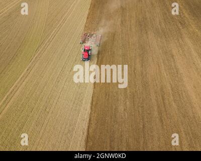 Luftaufnahme eines Traktors, der auf dem Land ein Stoppelfeld pflügt. Landwirtschaftlicher Traktor pflügt Bodenfeld für die Aussaat. Luftaufnahme von oben von der Drohne . Stockfoto