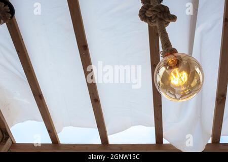 Seil Glühbirne über Leinwand Pergola Abdeckung. Low-Angle-Ansicht Stockfoto