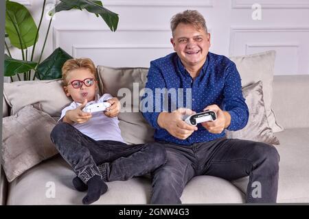 Boy spielt Videospiele mit glücklichen Großvater mit Spielkonsole. Stockfoto