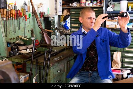 Professioneller Handwerker, der optische Sicht in der Waffenwerkstatt justiert Stockfoto