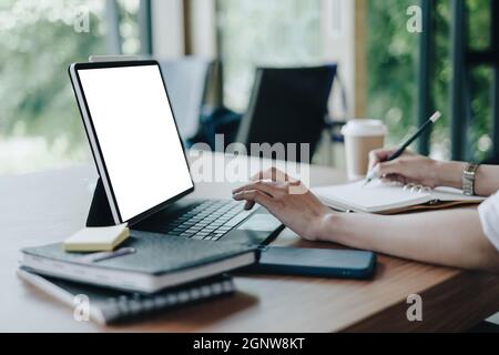Nachbildung eines digitalen Tablets mit weißem, leeren Bildschirm auf einem Holzschreibtisch. Stockfoto