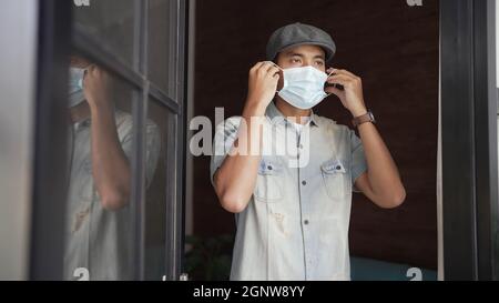 der asiatische Mann trägt eine Maske, bevor er sein Geschäft eröffnet Stockfoto