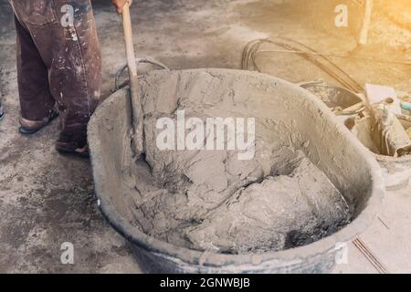 Arbeiter Mann Hausbauer mischen Mörtel aus einem Trog in Eimer Stockfoto