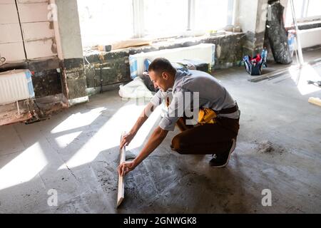 Arbeiter installieren den Boden. Reparaturman verfugen den Boden Stockfoto