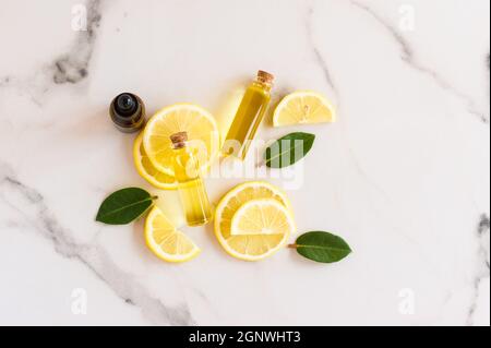 Draufsicht auf Scheiben von frischer Zitrone, Melisse und hellem Sonnenöl in Glasflaschen mit Korkdeckel. Natürliches Bio-Kosmetikprodukt Stockfoto