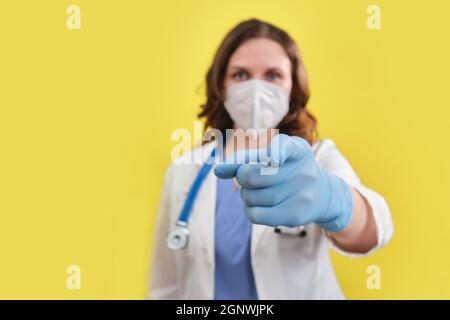 Ein Arzt in Uniform zeigt seinen Finger nach vorne auf Sie, Studiohintergrund Stockfoto
