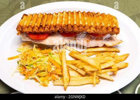 Kombinierter Teller mit einem Schweinelende-Sandwich und Pommes auf einer weißen Keramikplatte in einem Restaurant Stockfoto