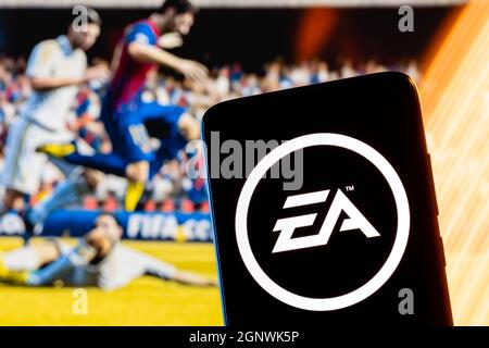 Electronic Arts-Logo auf dem Smartphone-Bildschirm. Ein Rahmen aus dem FIFA-Franchise-Spiel im Hintergrund. Stockfoto