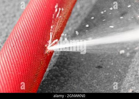 Eindringen von Wasser aus dem Loch in einem Schlauch Stockfoto