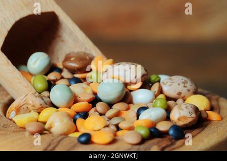 Auswahl verschiedener Hülsenfrüchte in einer Holzschale mit einem Holzlöffel. Nahaufnahme. Stockfoto