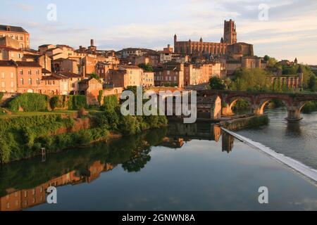 Kathedrale St. Cecile und Reflexionen der Stadt im Fluss Tarn, die kurz vor Sonnenuntergang in Albi, Tarn, Occitanie, Frankreich, rot leuchten Stockfoto