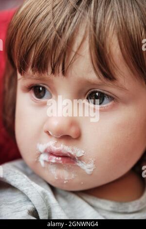 Baby Mädchen genießen ein Eis mit Creme rund um den Mund. Nettes Mädchen essen Eiscreme. Stockfoto