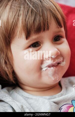 Baby Mädchen genießen ein Eis mit Creme rund um den Mund. Nettes Mädchen essen Eiscreme. Stockfoto