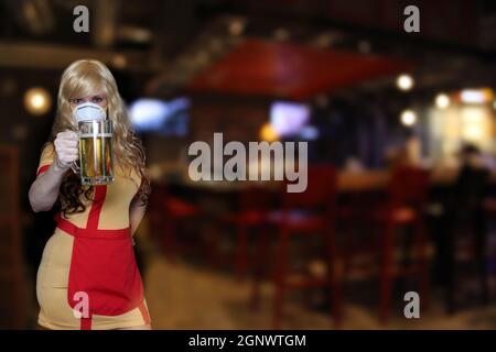 Kellnerin mit N95 Maske halten Bierbecher, flache DOF Fokus auf Bier Stockfoto