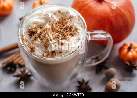 Herbstlicher, mit Kürbis gewürzter Latte mit Schlagsahne und Zimt, herbstlich vegane Heißgetränke mit Gewürzen, Zimt und Anissternen Stockfoto